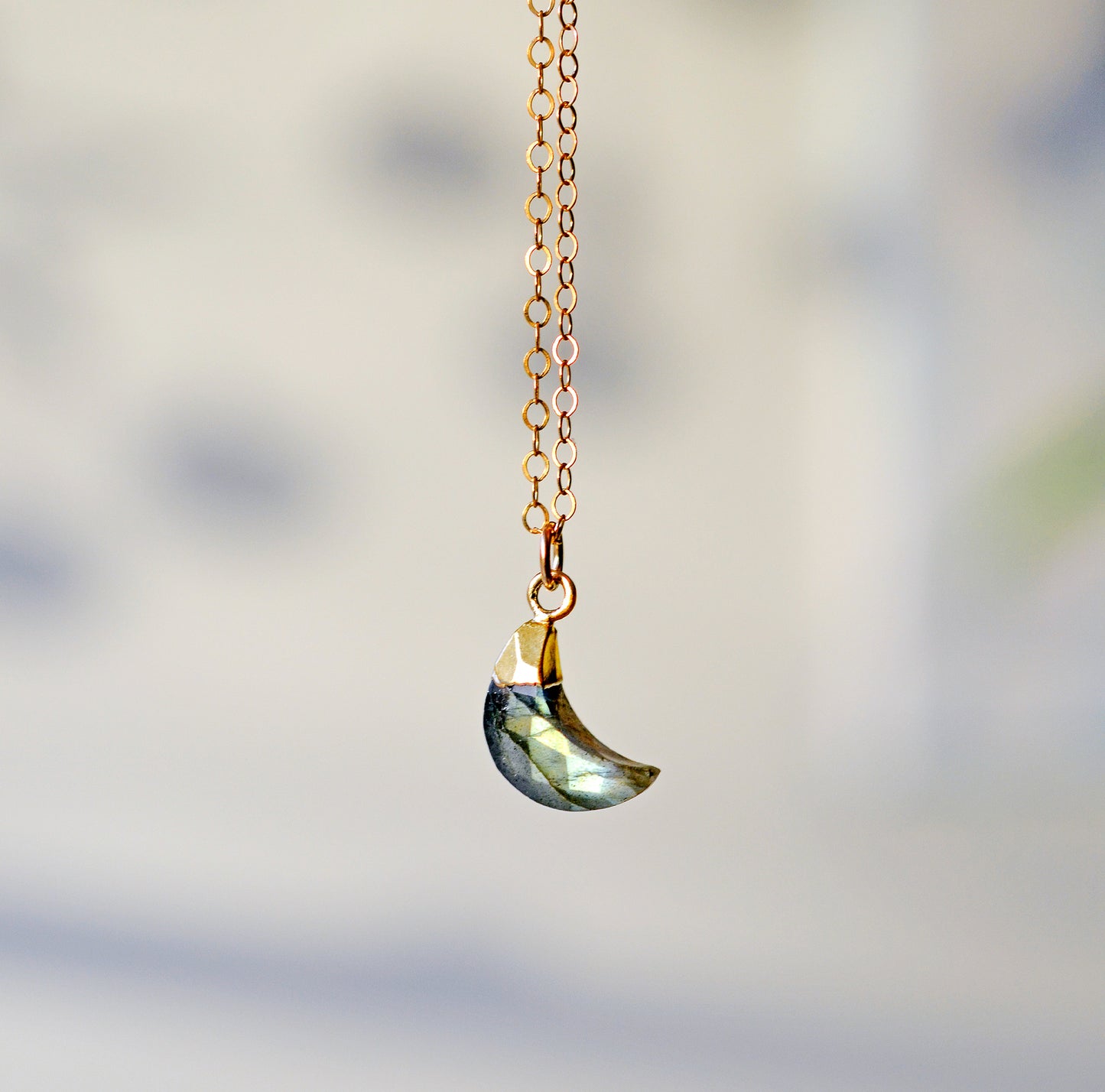 Necklace with a crescent moon pendant handmade with a natural labradorite gemstone set in gold. The chain is 14k gold filled.