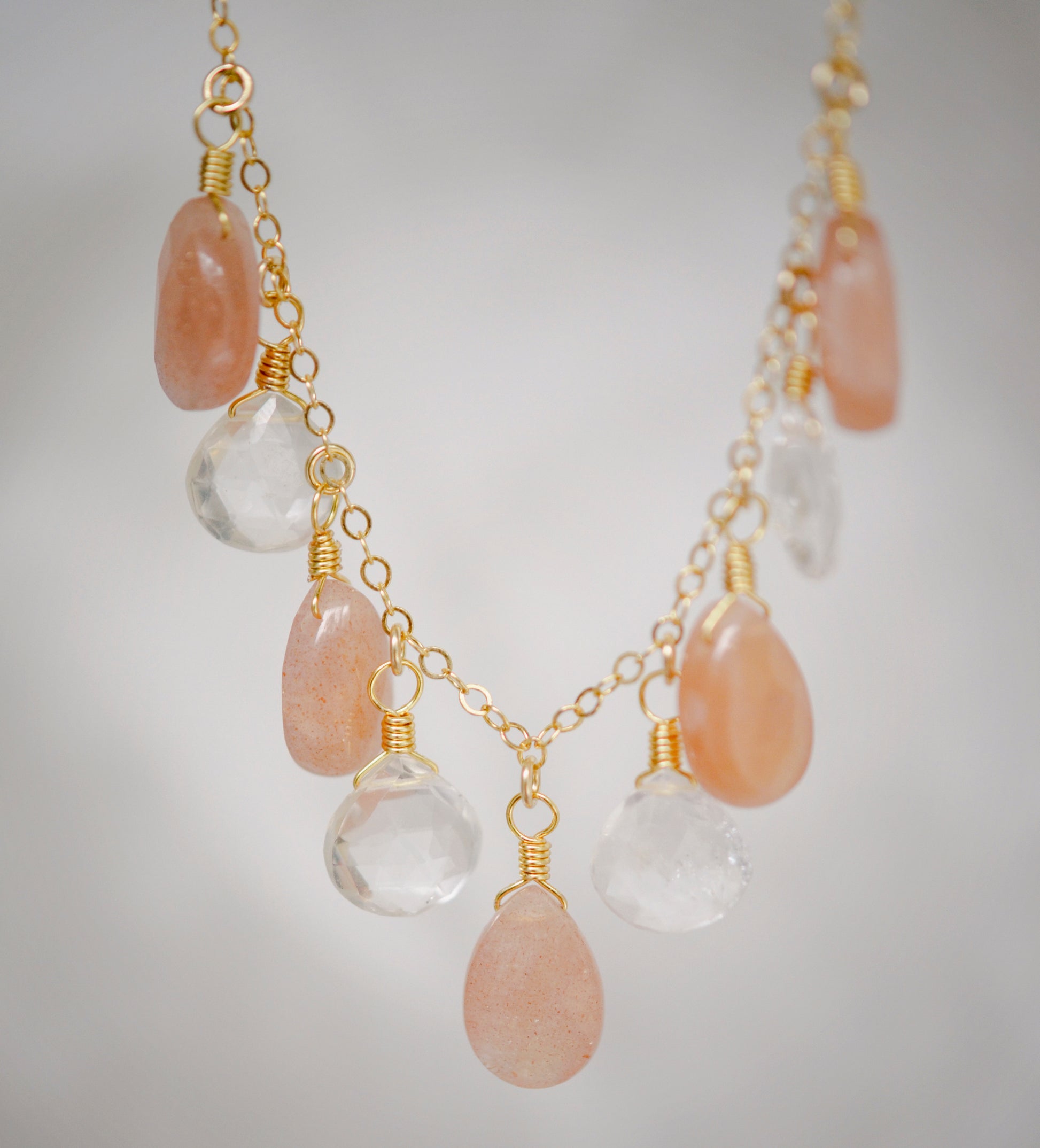 Orange, peach Sunstone and clear Crystal Quartz teardrops dangle off a 14k gold filled chain. 