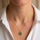 Modeled image of a small, natural moss agate circle pendant set on a 14k gold filled chain. This minimalist, delicate, smooth polished pendant is handmade in Connecticut by Gemnia Jewelry. Also available in sterling silver.