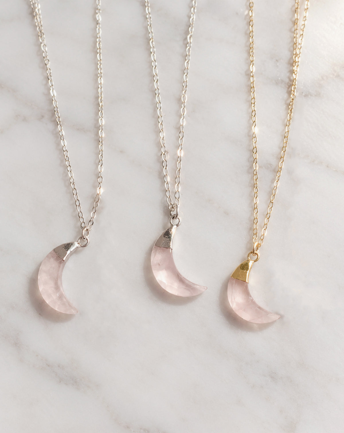 Three genuine pink rose quartz crescent moon necklaces shown in sterling silver or 14k gold filled. These dainty celestial pendants are handmade by Gemnia in Connecticut.