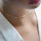 Modeled image of the natural white freshwater pearl chain necklace. Tiny freshwater pearls are mixed within a dainty cable chain in gold. Also available in sterling silver.