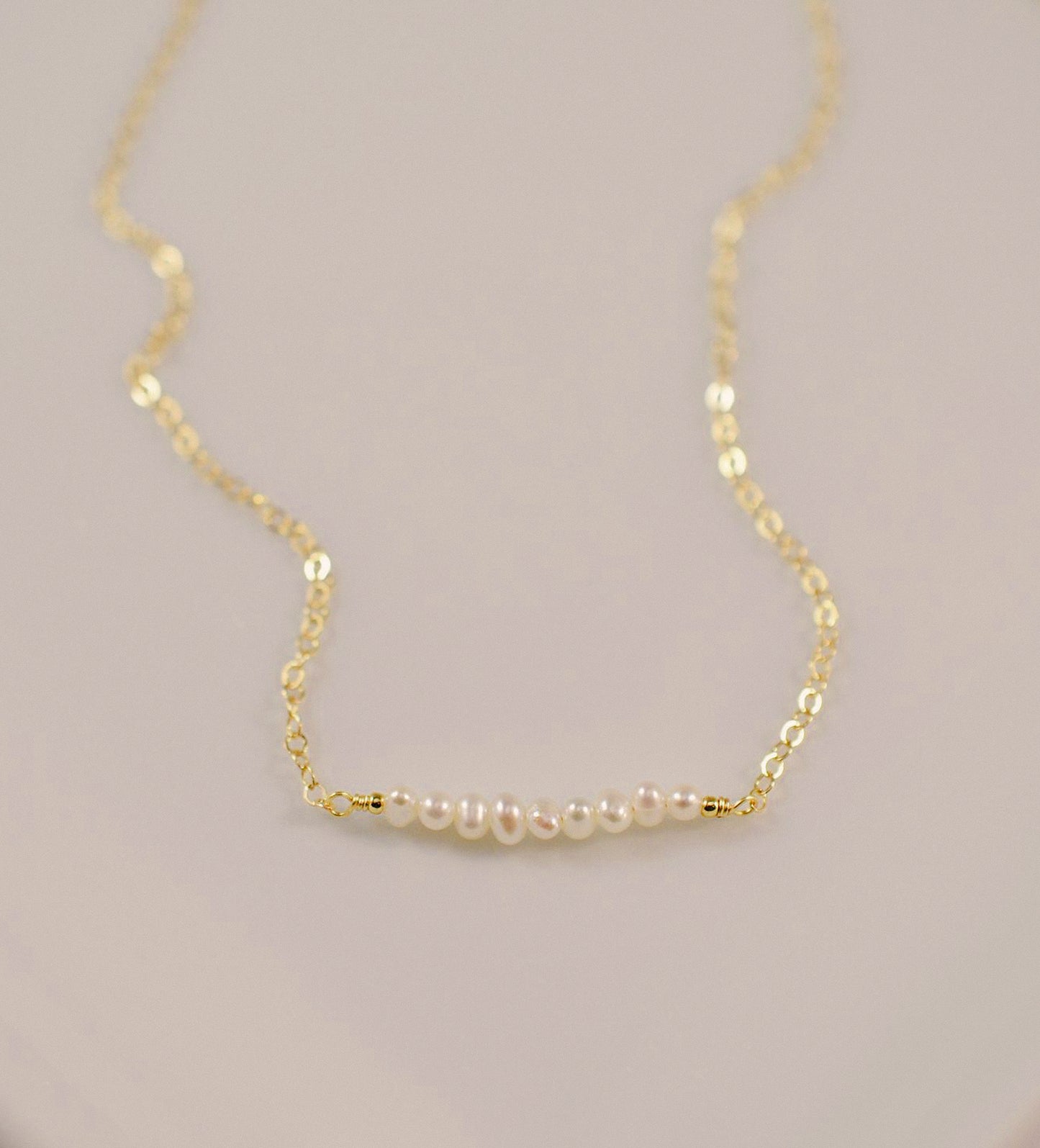 White freshwater pearl bar necklace shown in 14k gold filled. The peals are small and slightly irregular in shape.