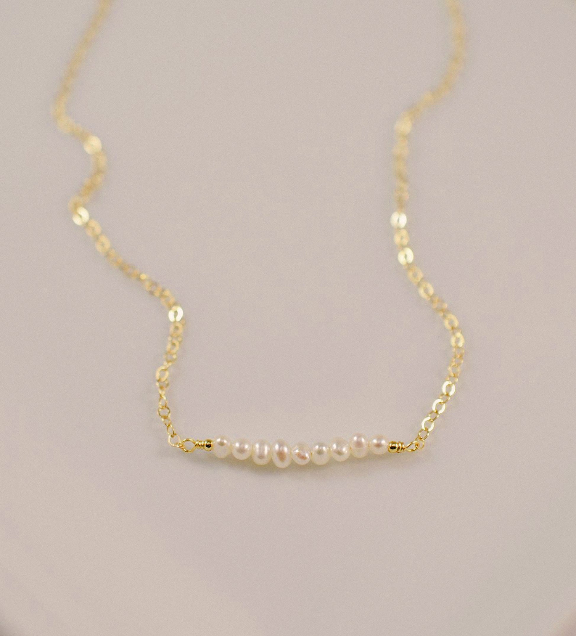 White freshwater pearl bar necklace shown in 14k gold filled. The peals are small and slightly irregular in shape.