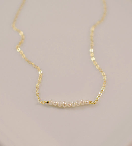 White freshwater pearl bar necklace shown in 14k gold filled. The peals are small and slightly irregular in shape.