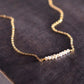 White freshwater pearl bar necklace shown in 14k gold filled. The peals are small and slightly irregular in shape.
