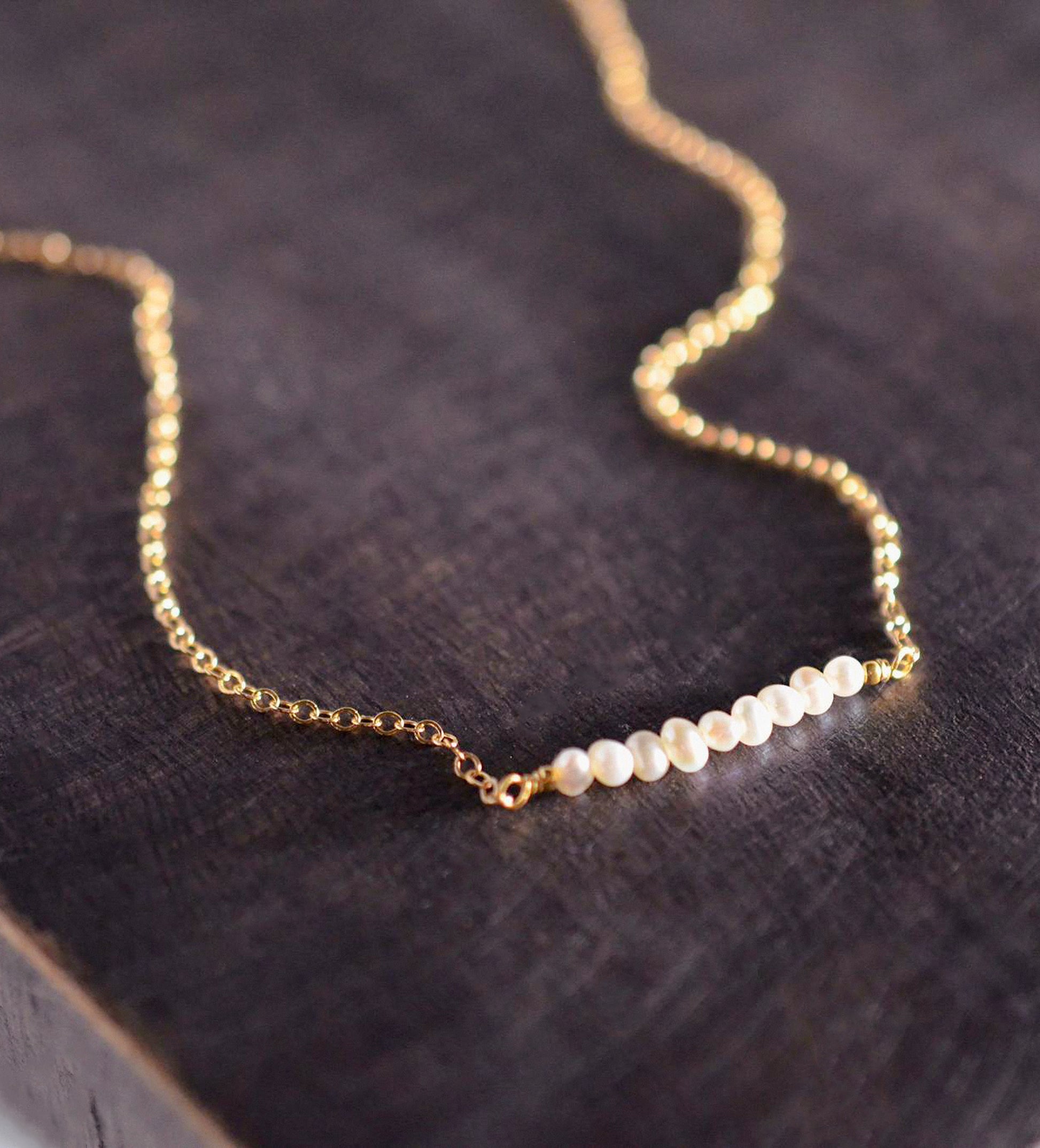 White freshwater pearl bar necklace shown in 14k gold filled. The peals are small and slightly irregular in shape.