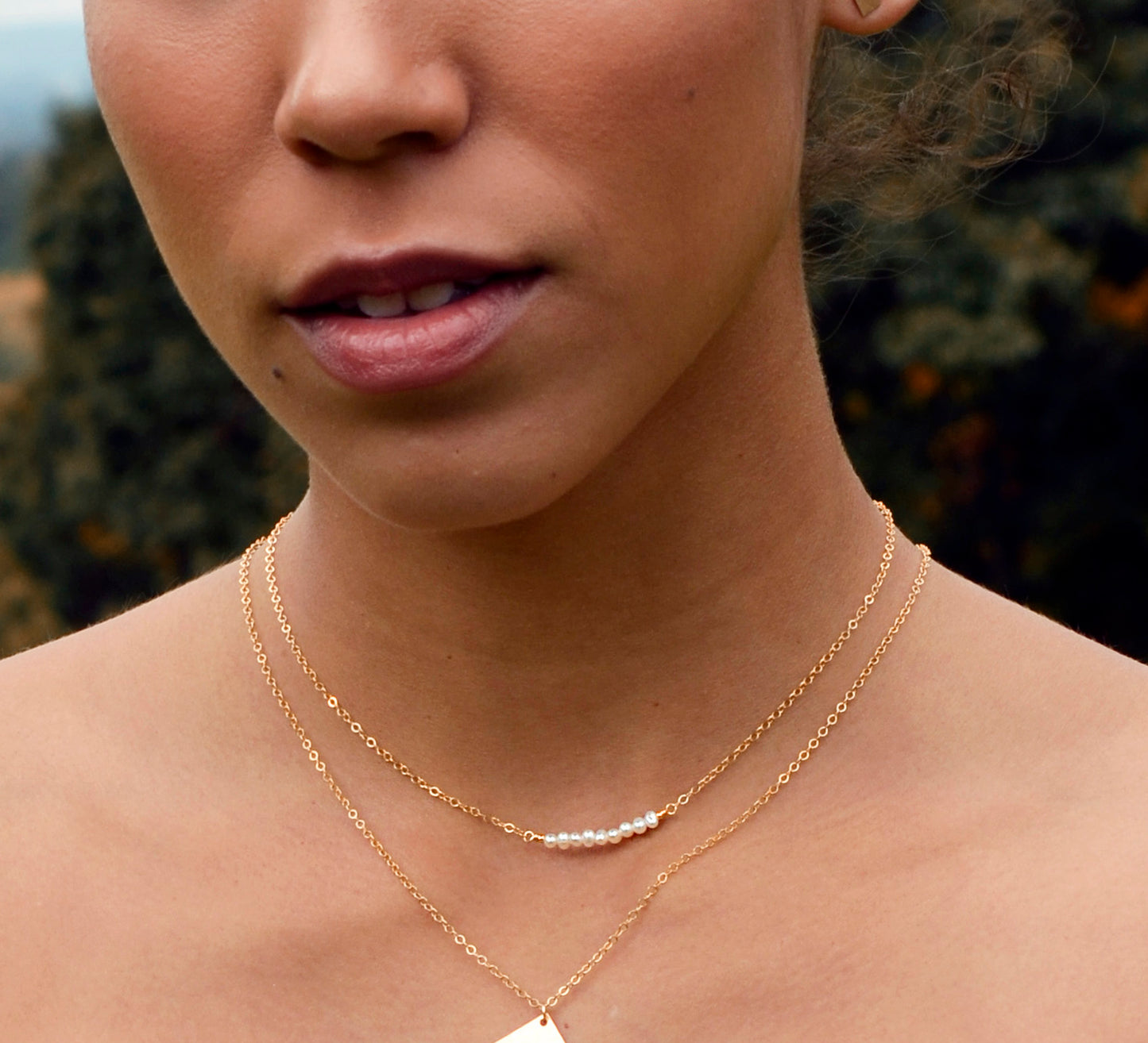 Modeled image of white freshwater pearl bar necklace shown in 14k gold filled. The peals are small and slightly irregular in shape.