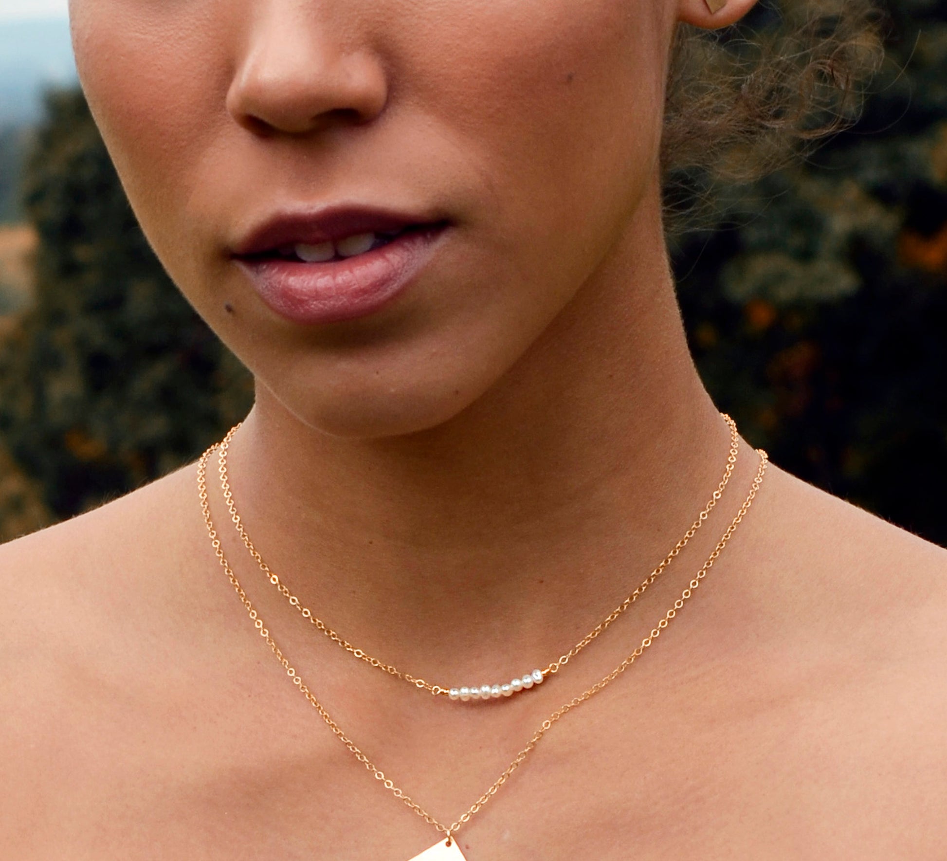 Modeled image of white freshwater pearl bar necklace shown in 14k gold filled. The peals are small and slightly irregular in shape.