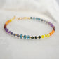 Beaded gemstone bracelet in rainbow colors. Handmade with natural gemstones including: yellow agate, orange carnelian, wine-red garnet, amethyst, tanzanite, topaz, and green emerald. Shown with a gold clasp.