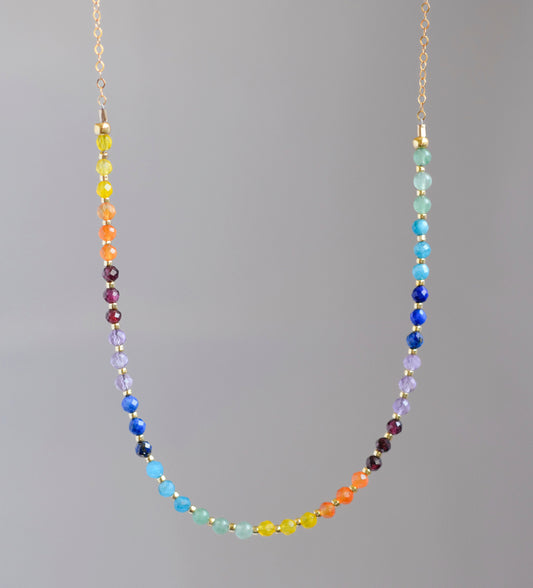 Rainbow chakra gemstone necklace. Crystals are beaded together in this pattern: yellow, orange, red, purple, blue, aqua, green. The gold style is shown.