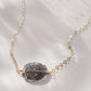Close up image of raw slice of natural black sunstone set on a 14k gold filled chain.