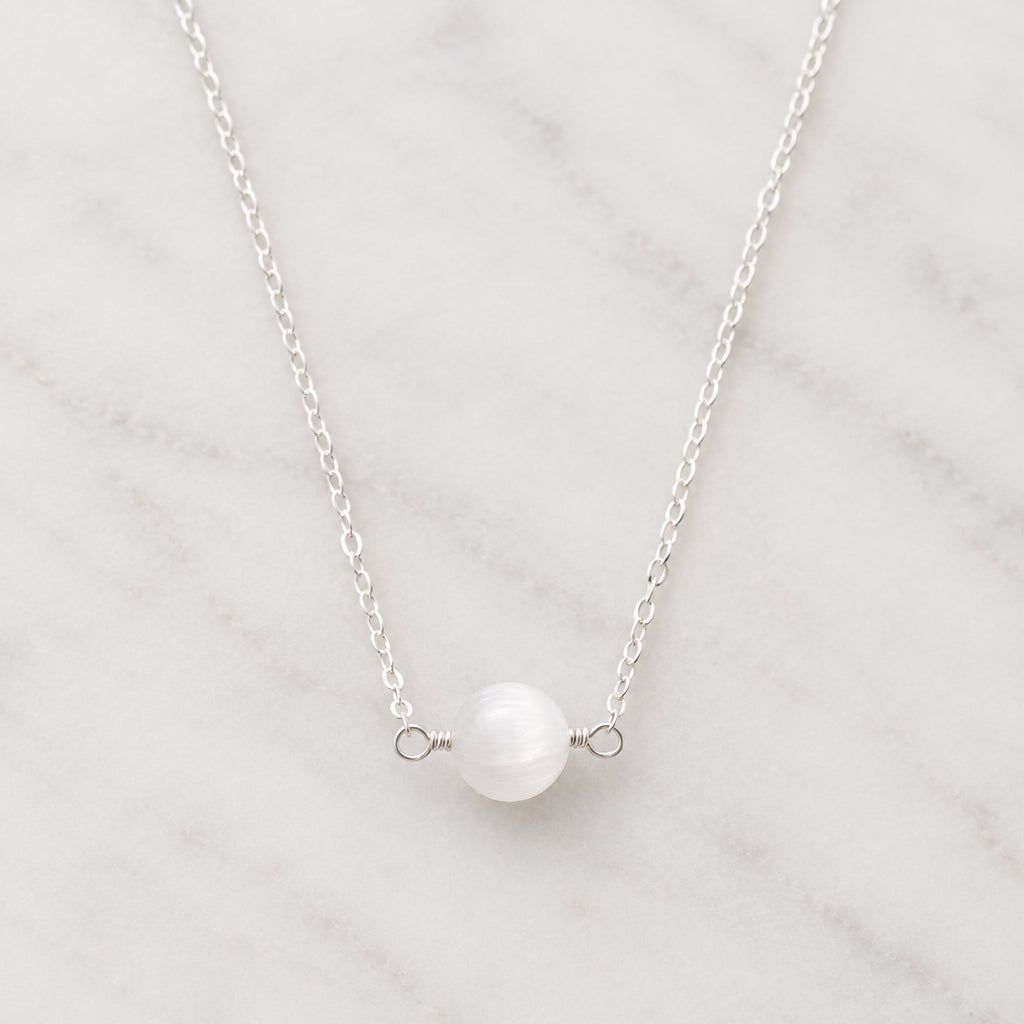 A genuine white selenite round stone set on a sterling silver chain. The crystal is smooth polished and handmade by Gemnia in New England.