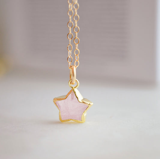 Dainty rose quartz star pendant necklace on a gold chain.