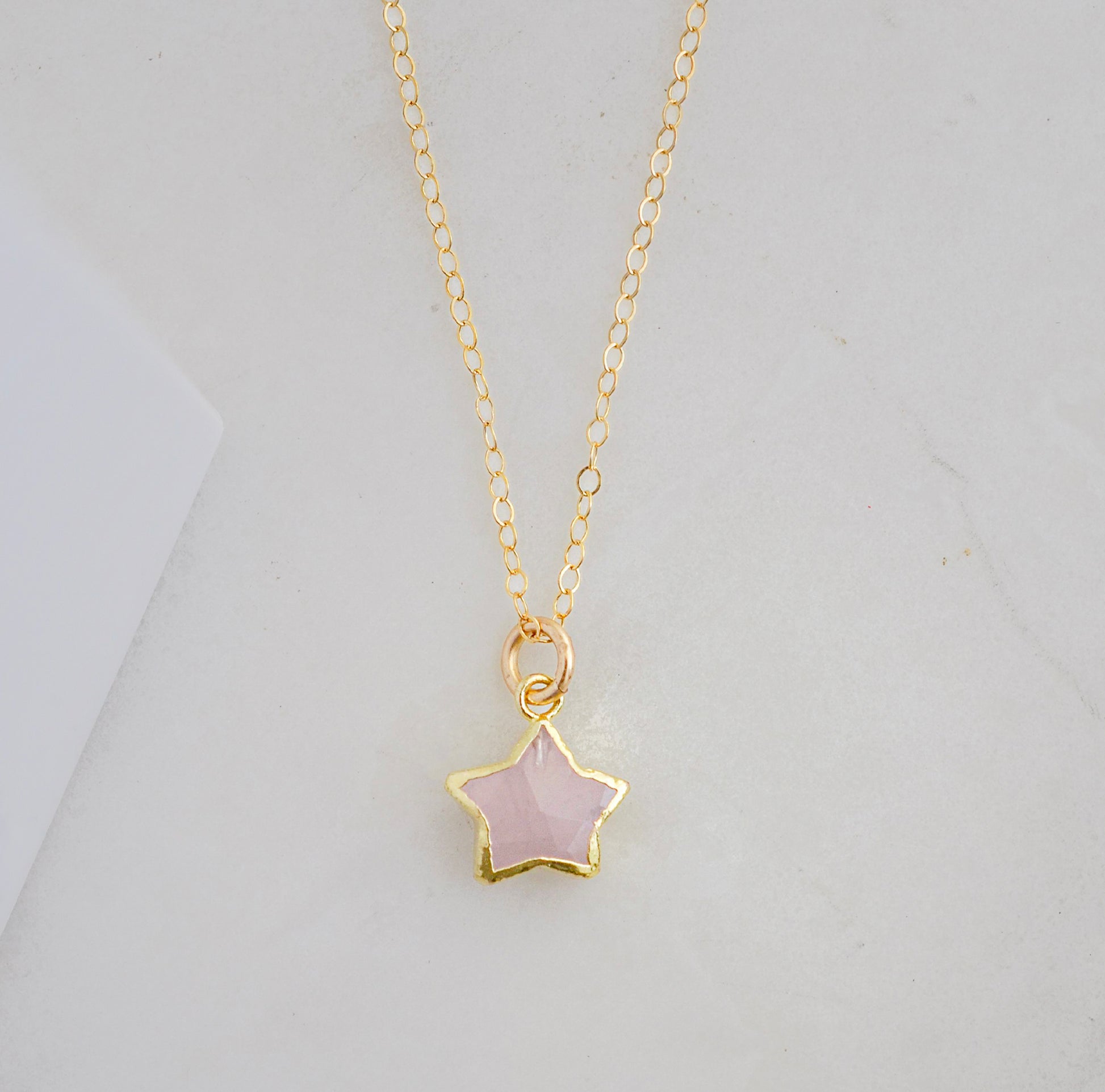 Dainty rose quartz star pendant necklace on a gold chain.