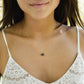 Woman wearing a dainty necklace with a dark gray to black quartz druzy gemstone  set on a 14k gold filled chain.