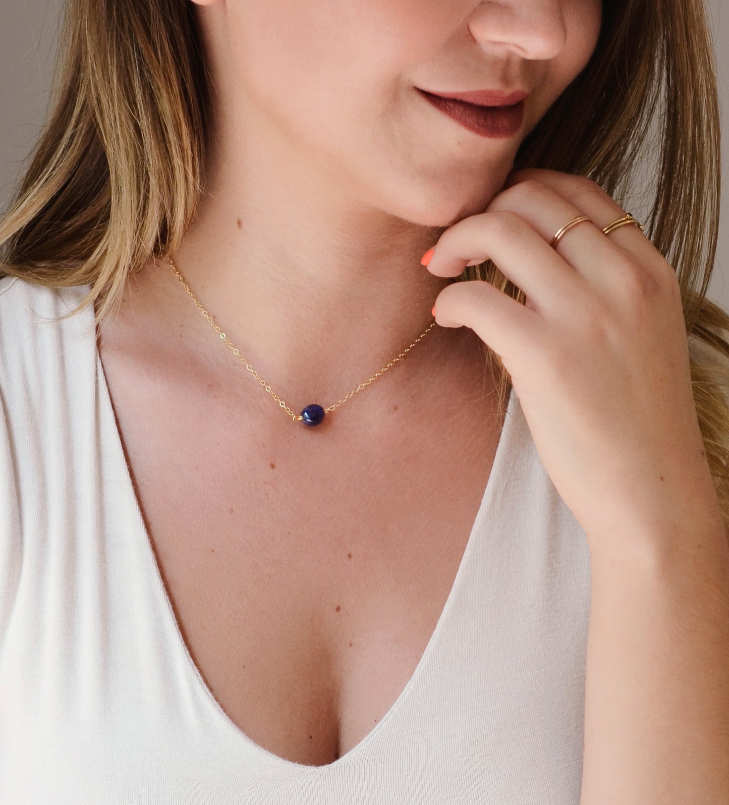 Small blue sapphire stone set onto a gold chain. The stone is a puffed oval shape. Modeled image.