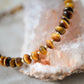 A close up image of a natural beaded tiger eye necklace in gold. All jewelry is handcrafted by Gemnia in Connecticut.
