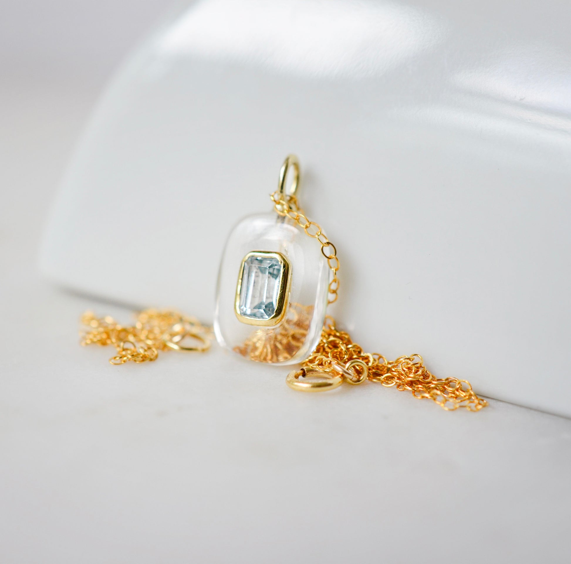 Handmade Maris necklace featuring a Blue Topaz set inside a clear Rock Crystal frame on a 14K Gold Filled chain. Ideal gift for wife, girlfriend, or mom. Minimalist topaz pendant for layering. Also a November birthstone.