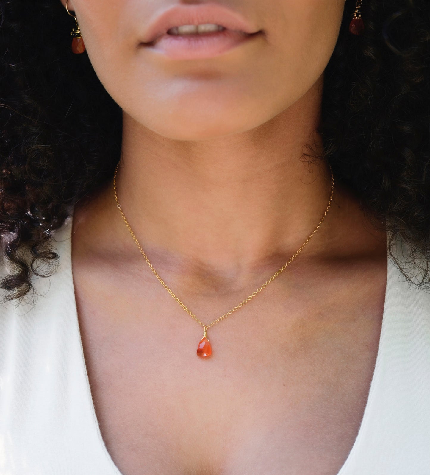 Natural orange triangular shaped Carnelian gemstone set onto a gold chain. Modeled image. 