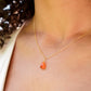 Natural orange triangular shaped Carnelian gemstone set onto a gold chain. Modeled image. 