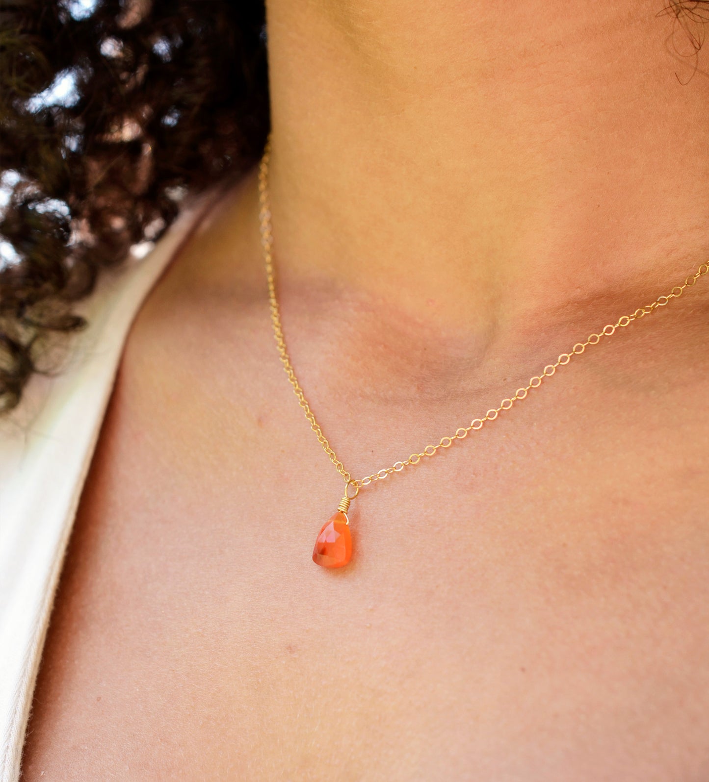 Natural orange triangular shaped Carnelian gemstone set onto a gold chain. Modeled image. 