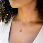 Natural orange triangular shaped Carnelian gemstone set onto a gold chain. Modeled image. 