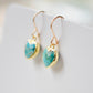 Genuine, natural blue turquoise faceted hearts set on 14k gold filled earring hooks. The stones range in blue and green, with some containing white or brown. Side view.