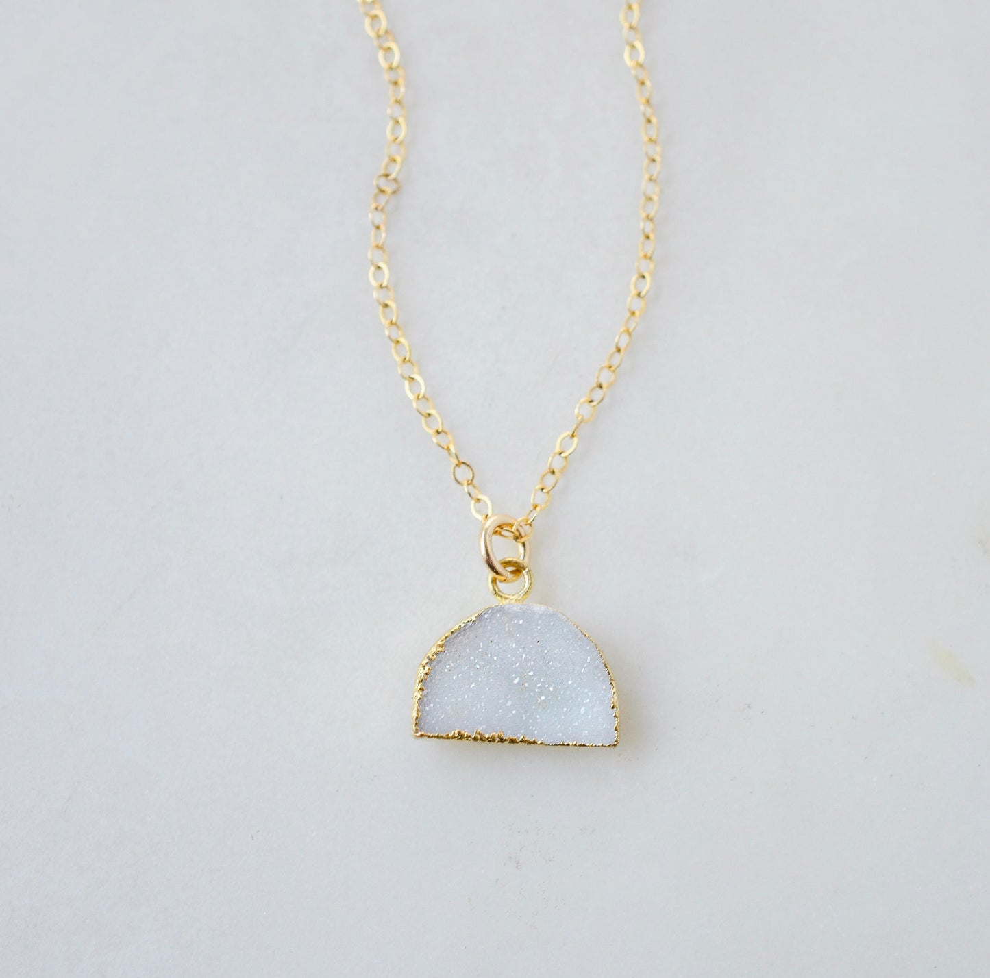 This necklace is handmade with a natural white druzy quartz pendant in a half-circle or crescent shape. Available in 14k gold filled.