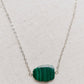 Natural green Malachite smooth polished slice with raw edges. Each stone is an irregular oval shape and has a variety of banding. Shown on a sterling silver chain.