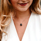 A modeled image of a woman wearing a rough, genuine, black tourmaline crystal necklace in sterling silver. The minimalist jewelry is handmade in Connecticut. 