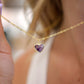 Natural purple amethyst heart stone pendant set onto a gold chain necklace.