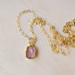 Pale pink Rhodochrosite smooth polished slice set in gold. Shown on a gold chain.