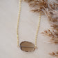 An irregular oval shape, smooth polished Smokey Quartz stone set onto a 14k gold filled chain. The stones edges are raw and irregular. 