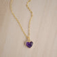 Natural purple amethyst heart stone pendant set onto a gold chain necklace.