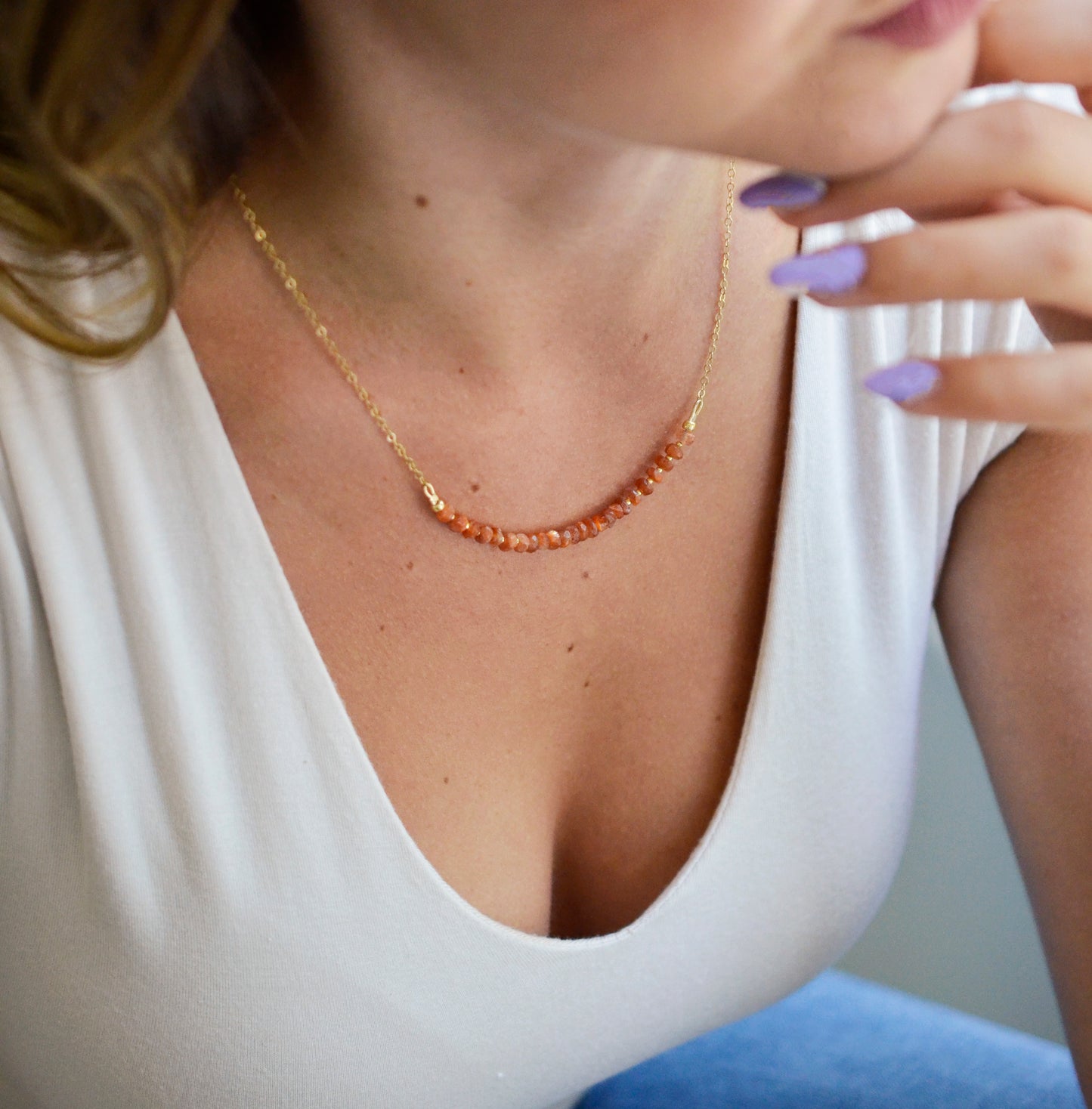 Handmade sunstone necklace featuring a row of beaded natural crystals. Modeled image.