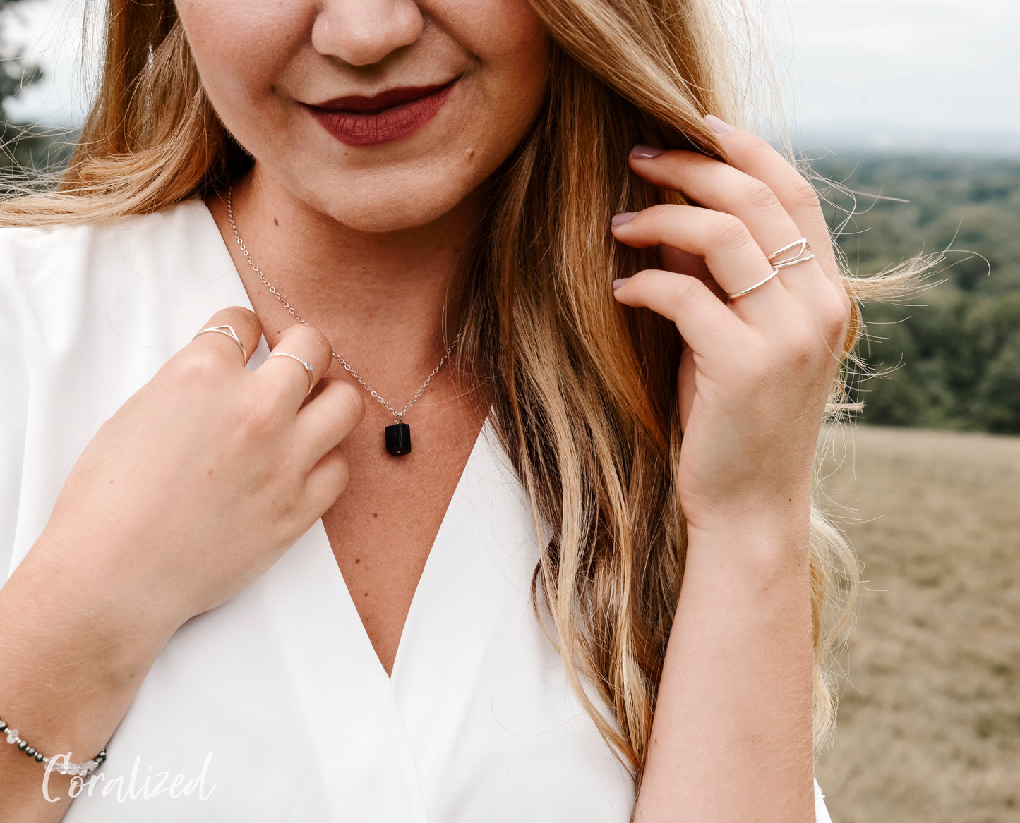A modeled image of a woman wearing a rough, genuine, black tourmaline crystal necklace in sterling silver. The minimalist jewelry is handmade in Connecticut. 