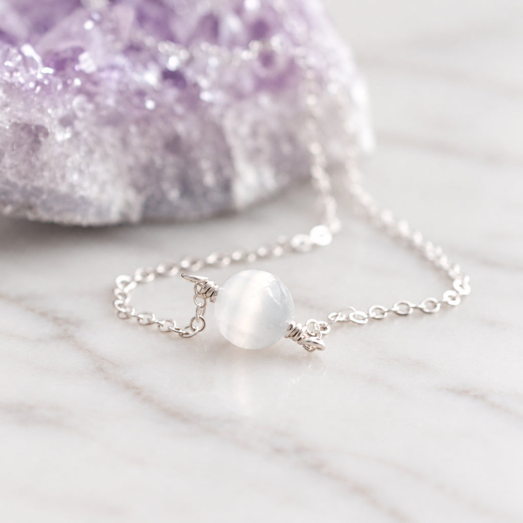 A close up image of a sterling silver necklace with a single stone of natural white selenite. Handmade jewelry in Connecticut by Gemnia.