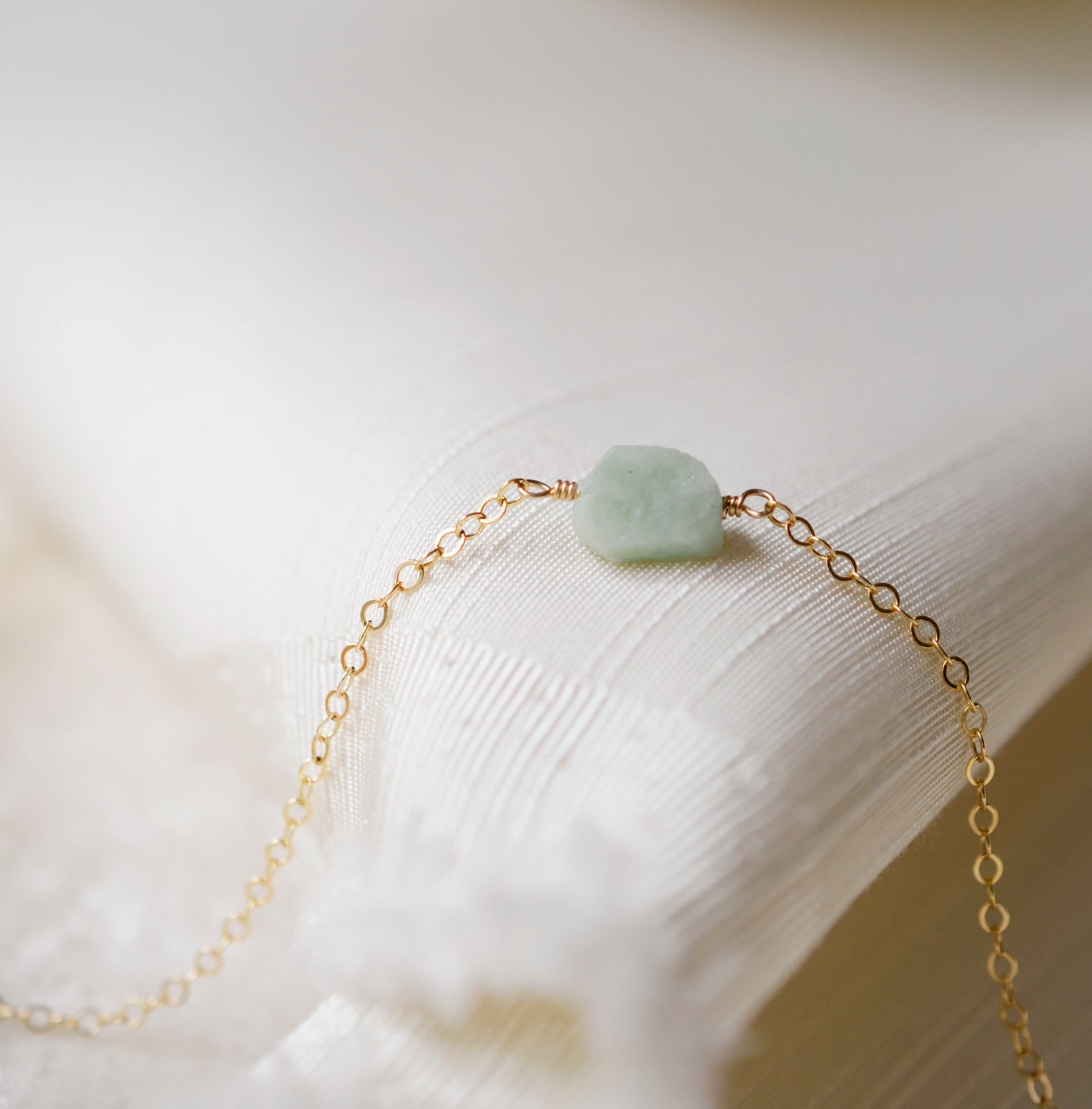 Pale green raw jade stone set onto a 14k gold filled chain. 