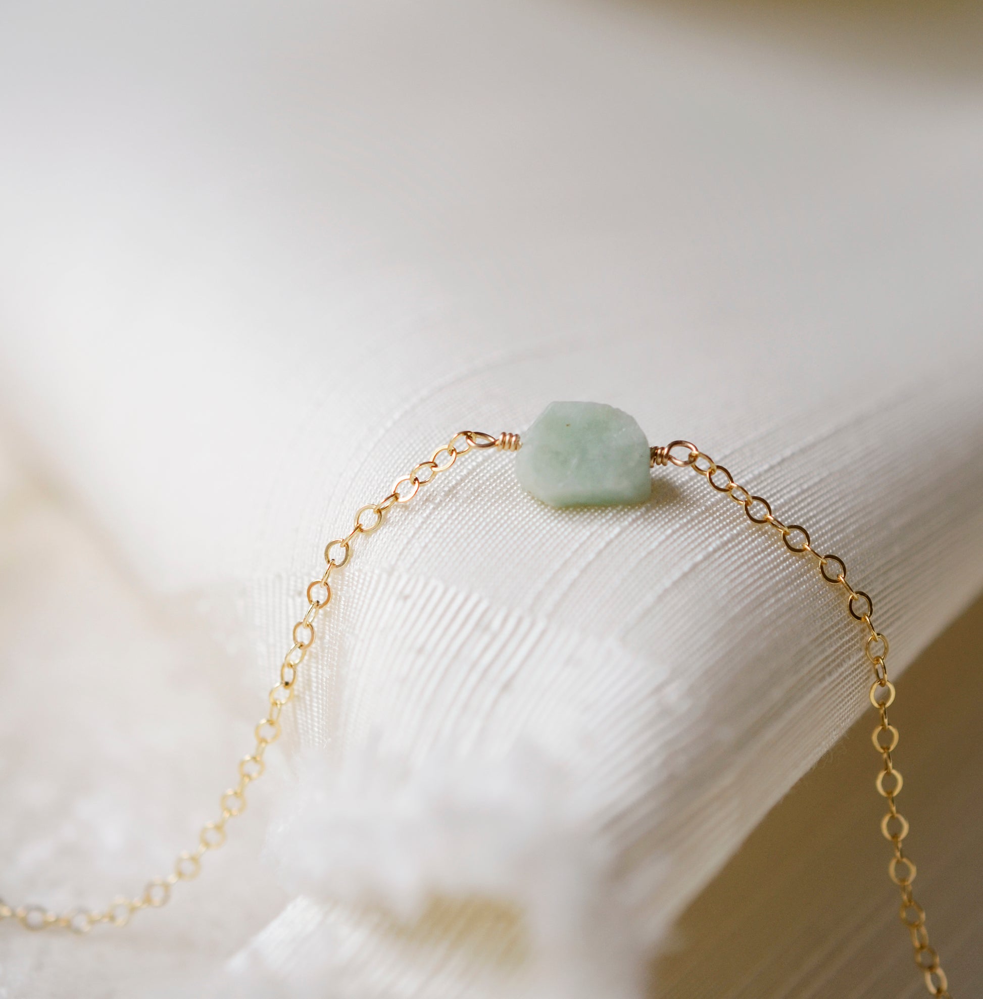Pale green raw jade stone set onto a 14k gold filled chain. 